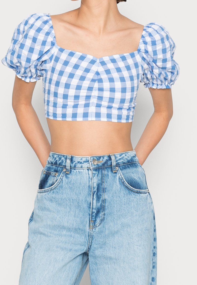 Blå og hvid ternet crop top med puffede ærmer og firkantet udskæring, parret med højtaljede lyse denim jeans.