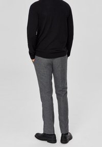 Czarny sweter, szare eleganckie spodnie, gładka faktura, prosta nogawka, noszone z czarnymi butami, widok od tyłu.