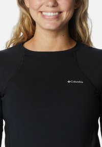 Schwarzes langärmliges Sportoberteil mit flachen Nähten und rundem Halsausschnitt, mit einem kleinen Columbia-Logo im linken Brustbereich.