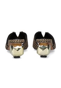 Mocasines de punto con un patrón de pata de gallo, en negro y beige, con un tacón geométrico metálico. Diseño de espalda abierta para facilitar su uso.