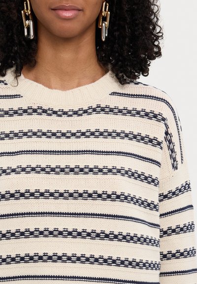 Maglione di lana beige con strisce orizzontali blu navy. Il design presenta un motivo testurizzato e un classico collo a giro.