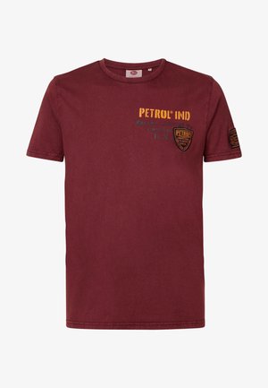 T-shirt en coton bordeaux avec col rond, manches courtes, et logos imprimés en jaune et vert, avec un patch sur la manche gauche.