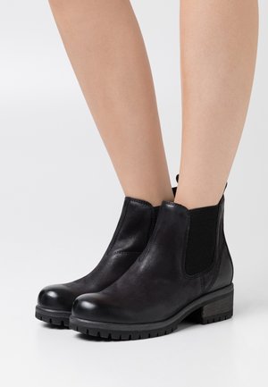Botas de cuero negro hasta el tobillo con paneles laterales elásticos, punteras redondeadas, upper texturizado y tacón bajo apilado. Suela de goma duradera con agarre.