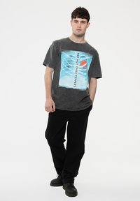 Gray graphic t-shirt with a large blue and red "Red Hot Chili Peppers" print. Paired with black pants and dark shoes. Simple design.