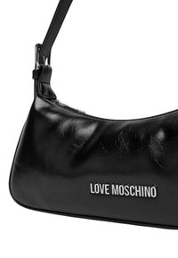 Bolso de hombro de cuero sintético negro con forma curvada, que presenta un logotipo en tono plateado y una textura suave y brillante.