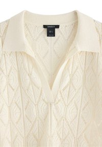 Stickad tröja i off-white med ett strukturerat geometriskt mönster, med V-ringning och en klassisk krage. Lappen visar storlek EUR S.