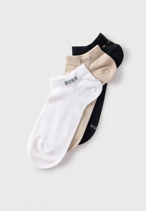 Drei Paar Knöchelsocken in Weiß, Beige und Schwarz, jeweils mit dem "BOSS"-Logo nahe der Bundkante.