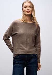 Brązowy sweter z dzianiny z długimi rękawami, okrągłym dekoltem i subtelną beżową poziomą fakturą, w połączeniu z ciemnoniebieskimi dżinsami.