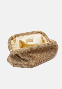 Guldartad kuvertväska med en texturerad utsida som har små cirkulära dekorationer och en slät satängfoder i guld.