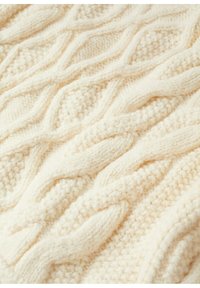 Tissu tricoté couleur crème avec un motif torsadé et diamant texturé, mettant en valeur un fil doux et épais ainsi qu'une couture détaillée.