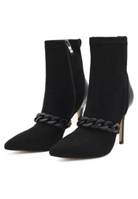 Stivaletti neri realizzati in suede e pelle con punta affusolata, decorazione a catena e zip laterale. Il tacco a stiletto completa il design.