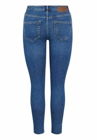 Jean ajustado de mezclilla azul, con tiro alto, bolsillos traseros cosidos y una pequeña etiqueta de cuero marrón en la cinturilla.