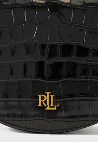 Fekete műbőr táska krokodilbőr textúrával, az alján aranyszínű, dombornyomott 'RLL' logóval és sima, fényes felülettel.