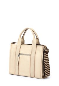 Beige lædertaske med to håndtag, frontlynlås lomme og et mønstret justerbart bånd i sort, guld og hvid.
