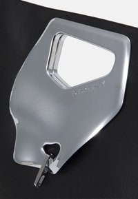 Geantă neagră cu un design al mânerului cromat, având un detaliu gravat "PUBLISHED BY". Feroneria pentru fermoar este de culoare argintie și integrată în design.