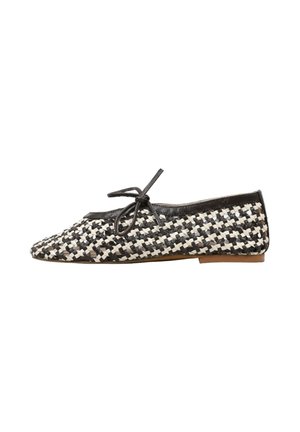 Chaussure de ballet plate tissée noir et blanc à motif croisillon, avec garniture noire et nœud sur le dessus, semelle beige, vue de côté.