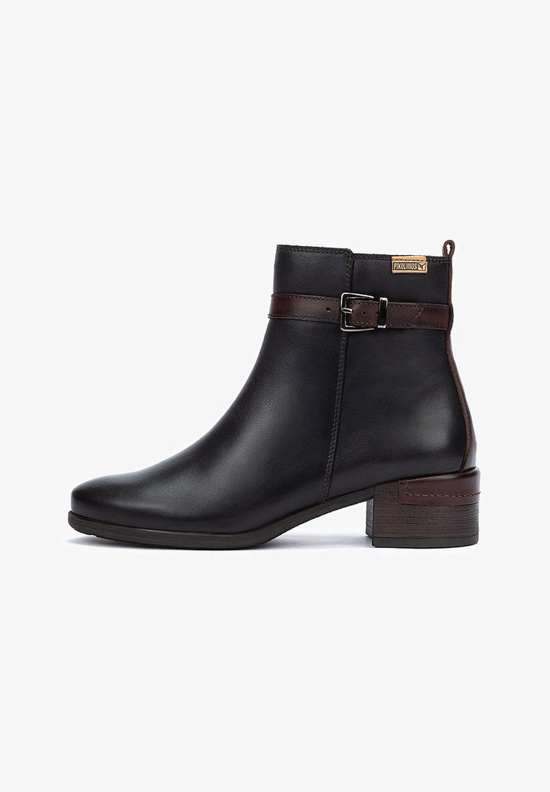 Botín de cuero negro con forma cónica, correa de cuero marrón y detalle de hebilla, y tacón de madera apilada. Textura suave en toda la superficie.