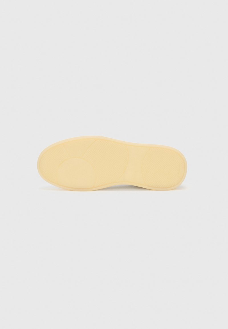 Gelbe Gummisohle mit strukturierten Mustern, die abgerundete Bereiche und ein Fischgrätenprofil für Grip und Traktion aufweist. Keine sichtbaren Markenkennzeichnungen.