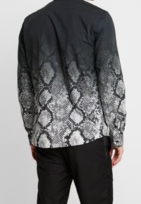 Long-sleeved shirt featuring a black to white gradient snake print design, with a smooth texture and button-down collar.