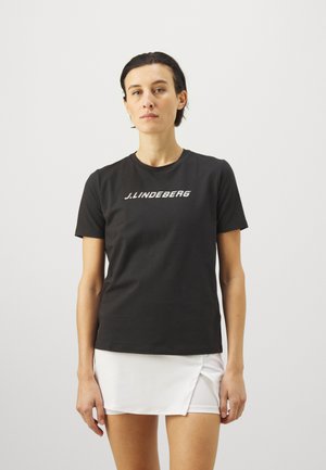 Black cotton t-shirt with short sleeves, featuring white "J. LINDEBERG" logo across the chest. Paired with a white skirt.