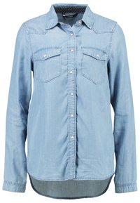 Ljusblå jeansskjorta med långa ärmar, två bröstfickor och tryckknapplåsnig. Har en rundad fåll och ett kragefoder med prickar.
