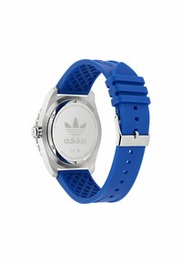 Modra silikonska zapestnica za uro z teksturiranim spodnjim delom, nerjaveča jeklena ohišje in vgraviran logotip Adidas na hrbtni strani. Okroglo številčnico z kovinskimi detajli.