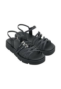 Sandali neri con una soletta testurizzata, multiple cinghie incrociate sottili e dettagli metallici. Suola spessa con un design a piattaforma.