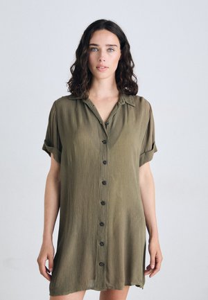 Olive green button-up dress with short rolled sleeves, textured fabric, and a straight cut, featuring five black buttons down the front.