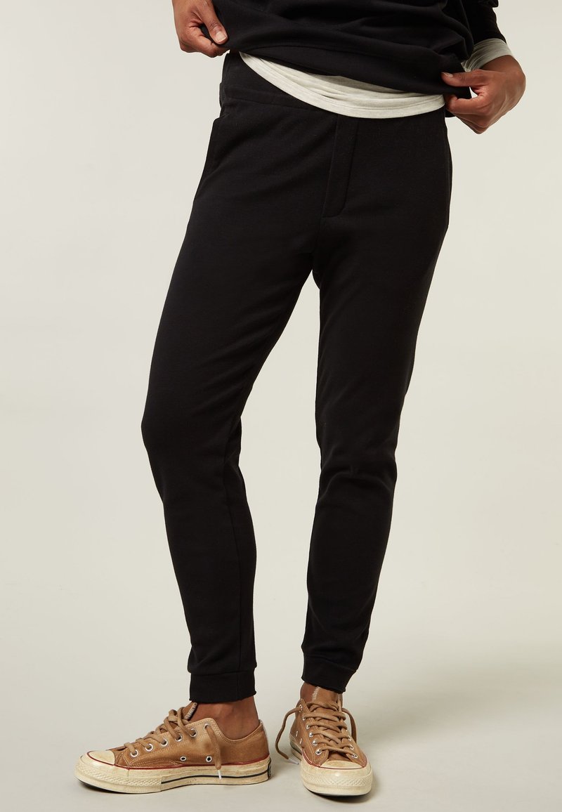 Zwarte sweatpants met een slim fit, gemaakt van zacht katoen, met een elastische tailleband en zijzakken, gecombineerd met brown canvas sneakers.