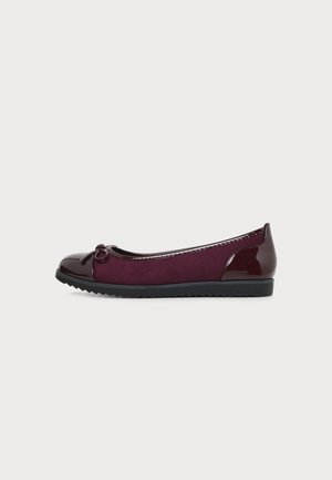 Chaussure plate bordeaux en daim et cuir verni, bout arrondi, petit nœud décoratif et semelle en caoutchouc noire à rainures.