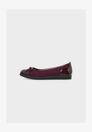 Chaussure plate bordeaux en daim et cuir verni, bout arrondi, petit nœud décoratif et semelle en caoutchouc noire à rainures.