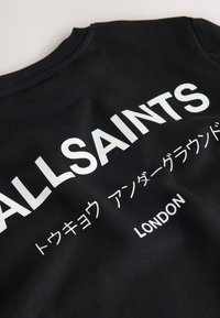 Czarna bluza z białym tekstem zawierającym "ALLSAINTS," japońskie znaki oraz "LONDON" nadrukowane z przodu.
