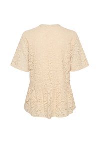 Cream lace blouse with short sleeves, floral pattern, round neckline, and peplum hem. Textured fabric with a delicate sheer appearance.