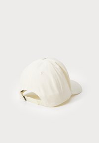 Hvit bomull baseballcap med rund krone, buet skjerm og justerbar bakrem. Har ventileringshull på sidene.