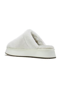 Chaussons en fourrure blanche avec un dessus en peluche, une conception ouverte à l'arrière et une semelle épaisse. Texture douce et doublure intérieure lisse pour un confort optimal.