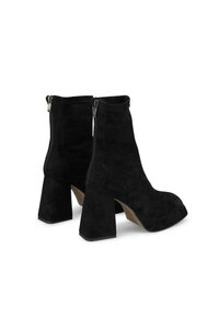 Czarne zamszowe botki za kostkę z wysokim słupkowym obcasem, okrągłym noskiem i bocznym zamkiem błyskawicznym. Gładka faktura, minimalistyczny design i jednolity kolor.