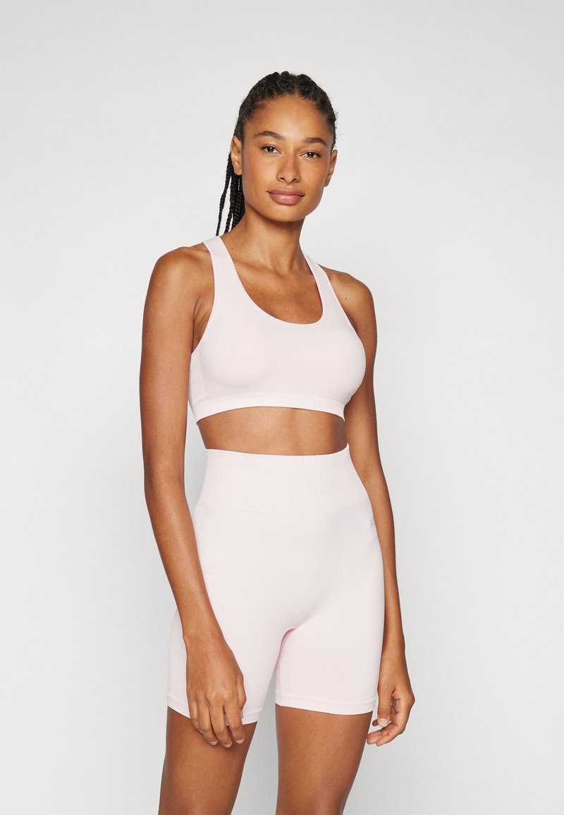 Sutiã desportivo rosa claro e calções de cintura alta feitos de um tecido elástico, apresentando um design sem costuras e uma cintura em malha.