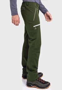 Dunkelgrüne Outdoor-Hosen aus robustem Material, mit Reißverschlusstaschen, verstärkten Knien und einem schlanken Schnitt.