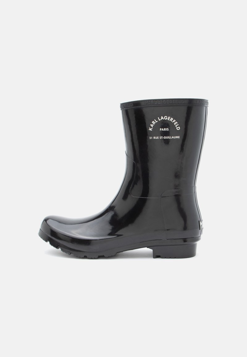 Botas de chuva pretas de borracha com bico arredondado, sola texturizada e logótipos em relevo na canela. Acabamento liso e brilhante, altura até ao tornozelo.