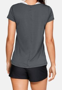 Camiseta atlética gris de manga corta con tela texturizada y un cuello redondo, combinada con pantalones cortos negros, vista desde la parte de atrás.