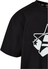 Sort bomulds t-shirt med et stort hvidt grafisk motiv af en stjerne og geometriske former. Kortærmet og med rund hals design.