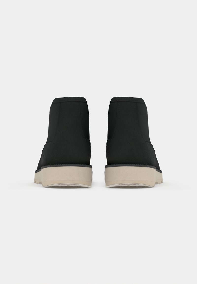 Stivaletti neri con tomaia in tessuto liscio, suola in gomma beige chiaro e un design semplice senza hardware o motivi visibili.