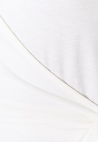 Tecido branco com uma textura suave e macia, apresentando uma dobra diagonal para o design. A cor é consistente em toda a superfície, sem padrões.