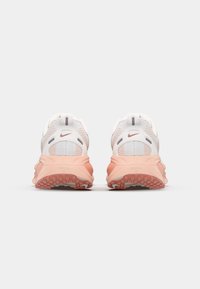 Scarpe da ginnastica bianche in rete con dettagli rosa, suole texturizzate e un design curvato. Presentano un'etichetta sul tallone e un logo vicino al tallone.