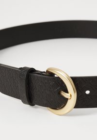 Black belt made of embossed leather featuring a round gold-tone buckle. Includes holes for adjustment and a smooth texture.