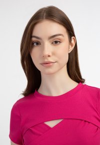 Feszes magenta felső, bordázott textúrával, rövid ujjakkal és átlós kivágással a nyak alatt. Sima felület, modern dizájn.