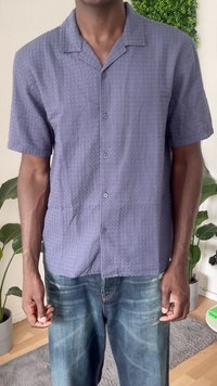 Kurzärmliges, strukturiertes Hemd in Dunkelblau mit Knopfleiste und einem weichen, gewebten Design. Trägt dazu eine hellblaue, vernietete Jeans.