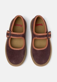 Zapatos estilo Mary Jane marrones con una correa y hebilla marrones, que presentan un interior de malla, mostrados sobre un fondo blanco.