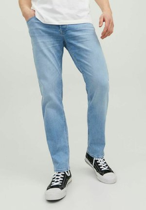 Light blue denim jeans with a straight-leg cut, five-pocket design, and subtle whiskering. Paired with black and white sneakers.