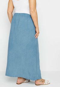 Ljusblå, lång denimkjol med elastisk midja och subtila veck. Slät textur, ankellång med rak passform och avslappnad design.